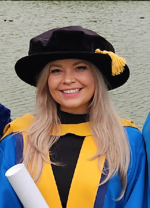 A smialing student in graduation robes
